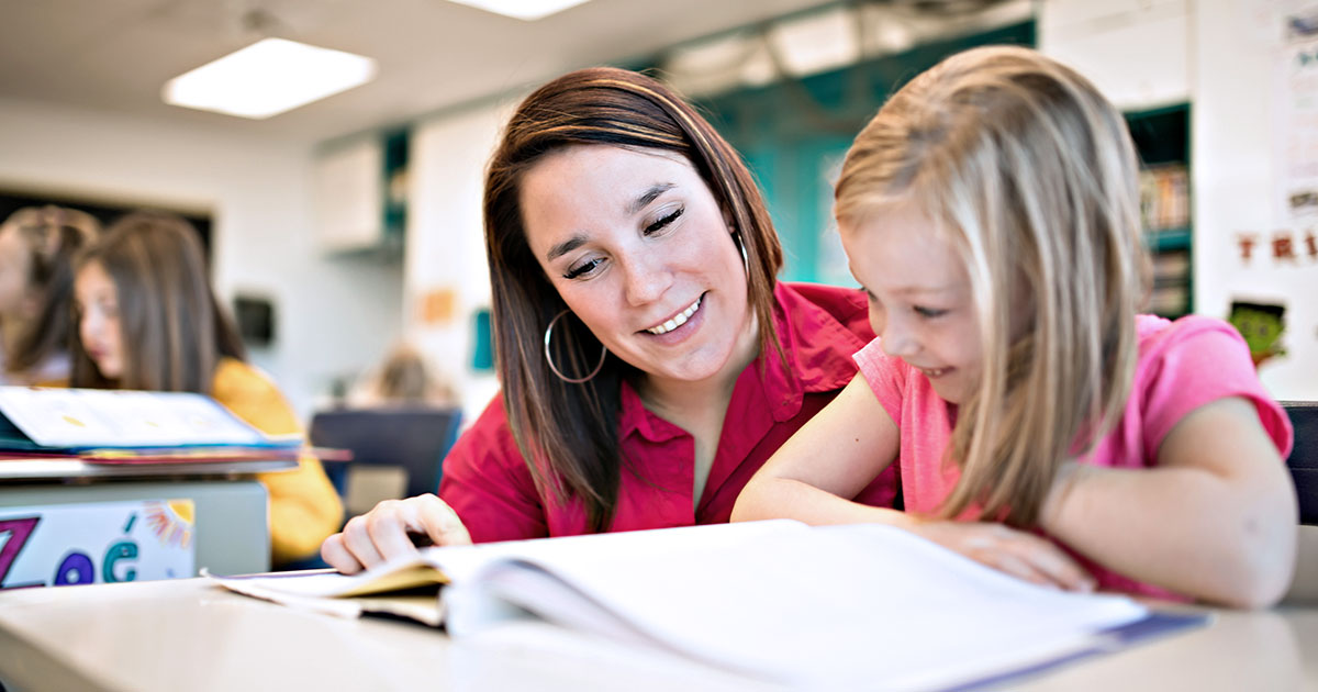 A teacher helping an early elementary school student to read